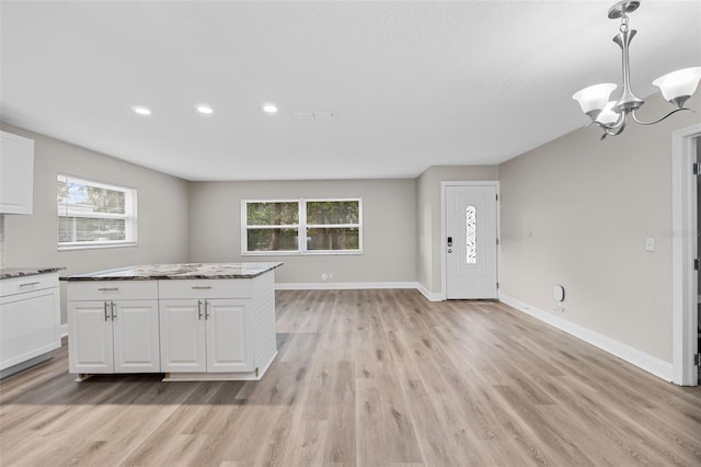 kitchen with white cabinets, light hardwood / wood-style flooring, a chandelier, and decorative light fixtures