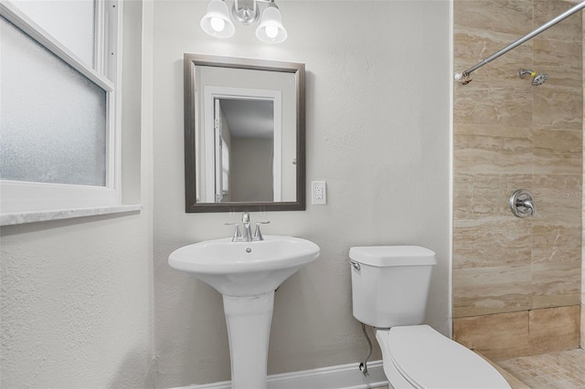 bathroom with a tile shower, sink, and toilet