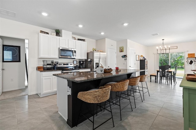 kitchen with a kitchen bar, a center island, a notable chandelier, white cabinetry, and appliances with stainless steel finishes