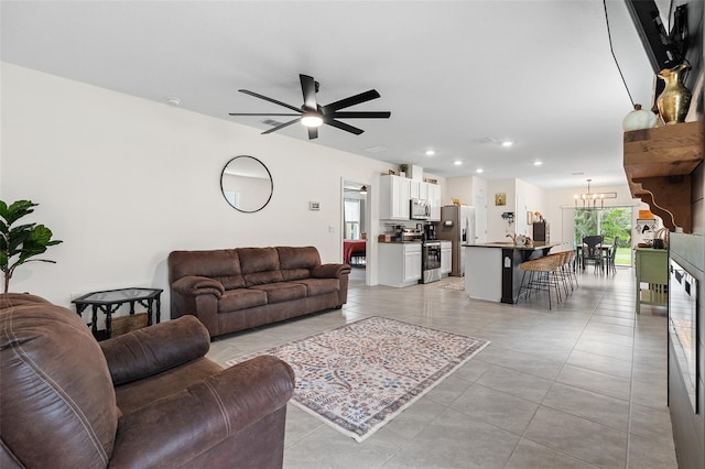 tiled living room featuring sink and ceiling fan with notable chandelier