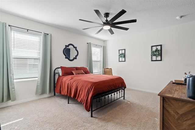 carpeted bedroom featuring multiple windows, a textured ceiling, and ceiling fan