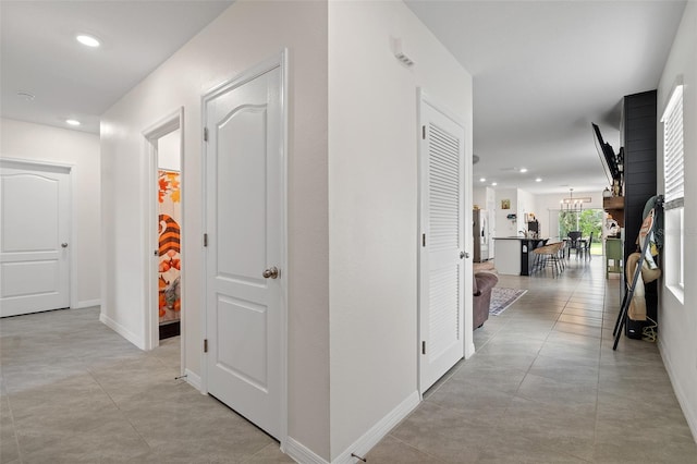 hallway featuring light tile patterned floors and a notable chandelier