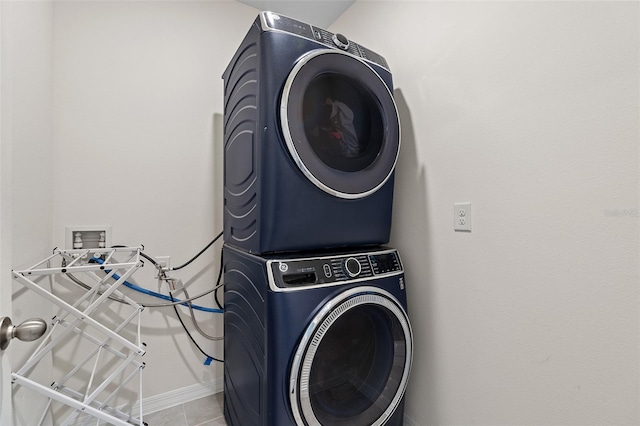 laundry area featuring tile patterned floors and stacked washer and clothes dryer