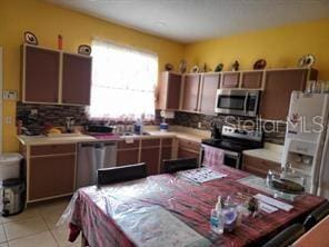 kitchen with tasteful backsplash, light tile patterned flooring, and stainless steel appliances