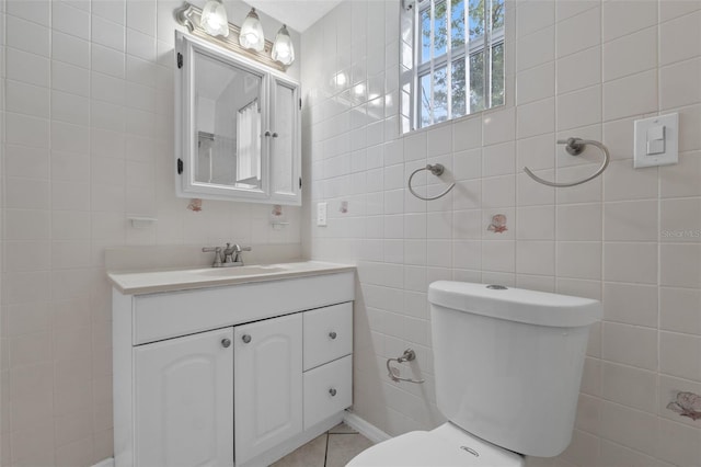 bathroom featuring toilet, vanity, and tile walls