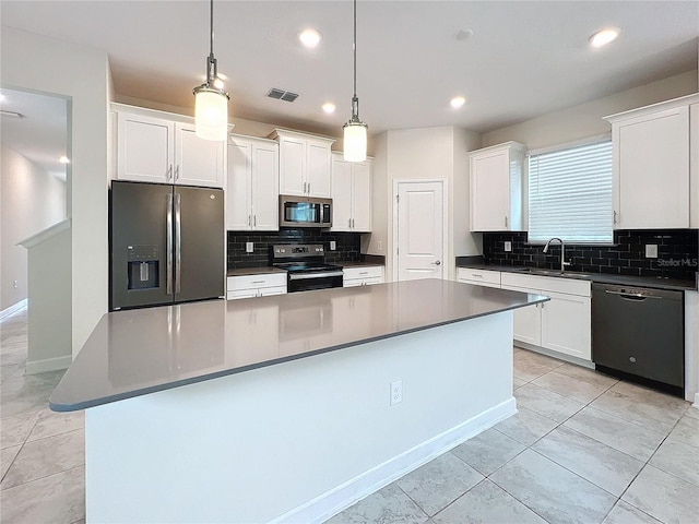 kitchen with light tile patterned floors, decorative light fixtures, a kitchen island, white cabinetry, and stainless steel appliances