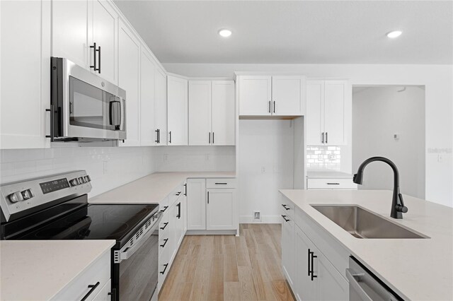 4060 Bannock Ave, Tavares, FL 32778 - kitchen with appliances with stainless steel finishes, a sink, light wood-style floors, white cabinetry, and recessed lighting