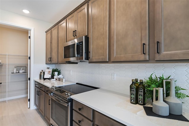 kitchen featuring stainless steel appliances, light countertops, decorative backsplash, and recessed lighting