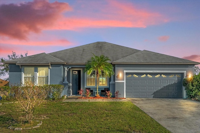 ranch-style home featuring a garage and a yard