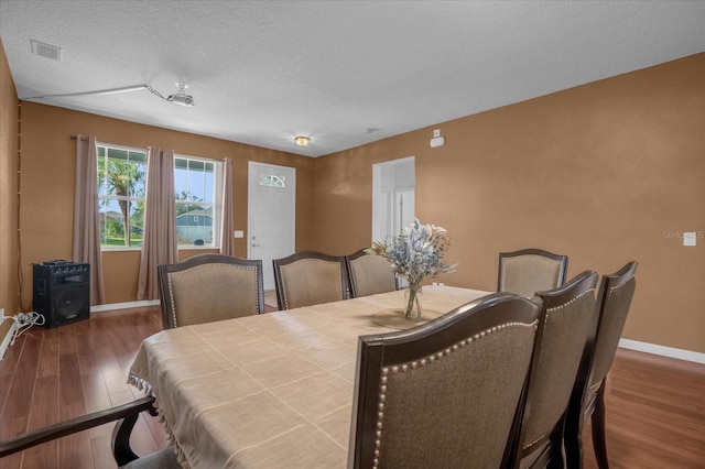 dining space featuring dark hardwood / wood-style flooring and a textured ceiling