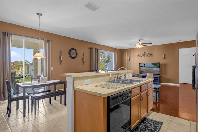 kitchen featuring dishwasher, sink, an island with sink, pendant lighting, and light wood-type flooring