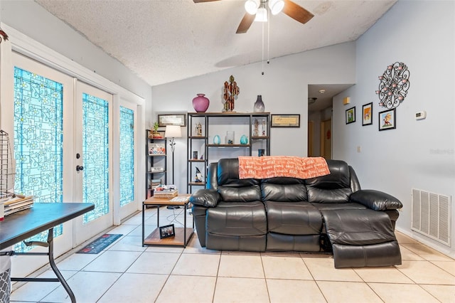 living room with a textured ceiling, ceiling fan, light tile patterned floors, and vaulted ceiling