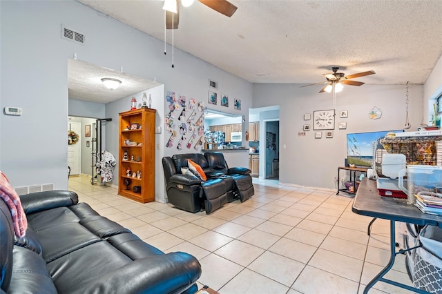 living room with ceiling fan, light tile patterned flooring, lofted ceiling, and a textured ceiling