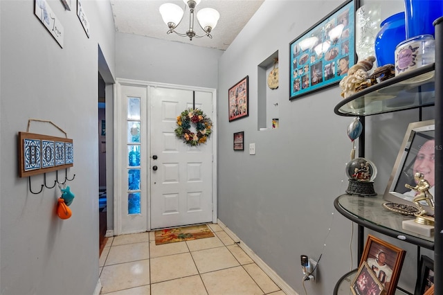 foyer featuring light tile patterned floors, a textured ceiling, and a notable chandelier