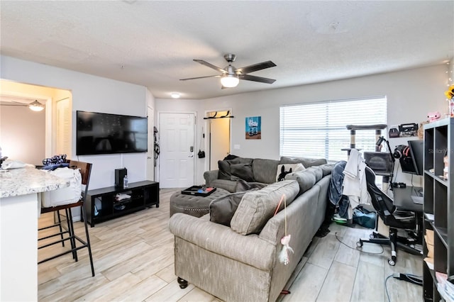 living room with a textured ceiling, light hardwood / wood-style flooring, and ceiling fan