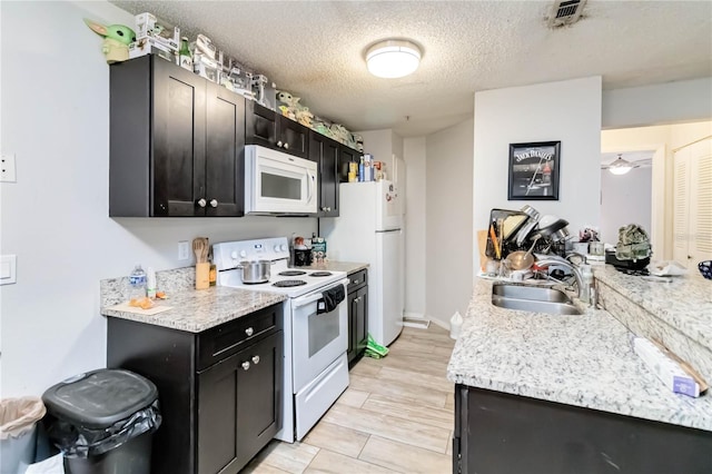 kitchen with light wood-type flooring, a textured ceiling, white appliances, ceiling fan, and sink