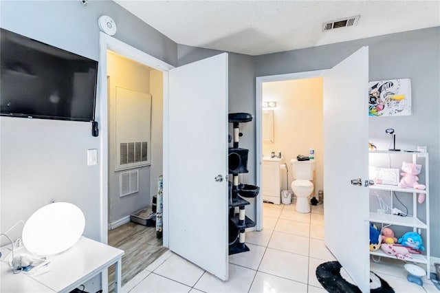 bathroom featuring toilet, a textured ceiling, and tile patterned floors