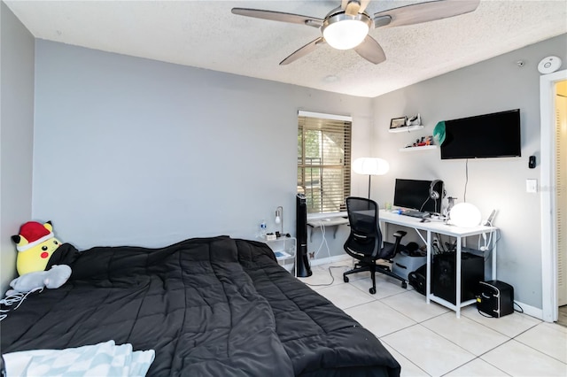 bedroom with ceiling fan, light tile patterned floors, and a textured ceiling