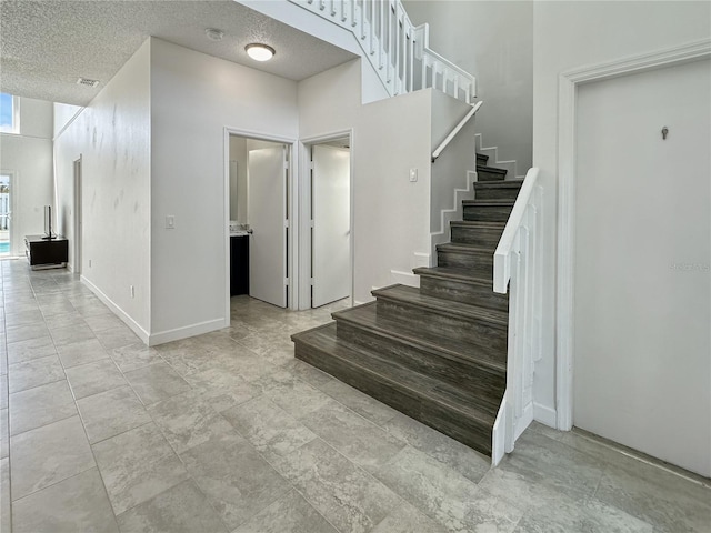 stairs featuring a textured ceiling