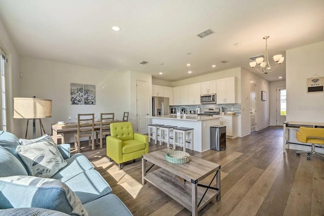 living room with sink, dark hardwood / wood-style floors, and an inviting chandelier