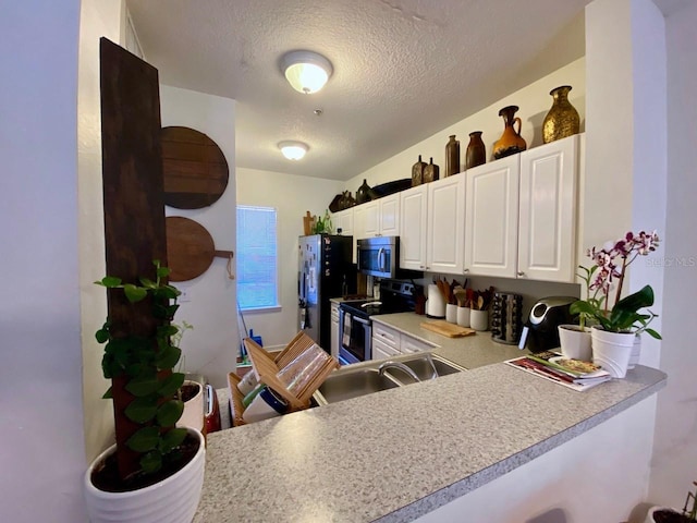 kitchen with kitchen peninsula, white cabinetry, a textured ceiling, and appliances with stainless steel finishes