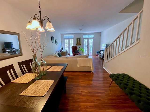 dining space with french doors, dark hardwood / wood-style floors, and an inviting chandelier