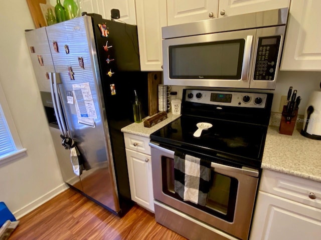 kitchen featuring white cabinetry, light hardwood / wood-style flooring, light stone countertops, and appliances with stainless steel finishes