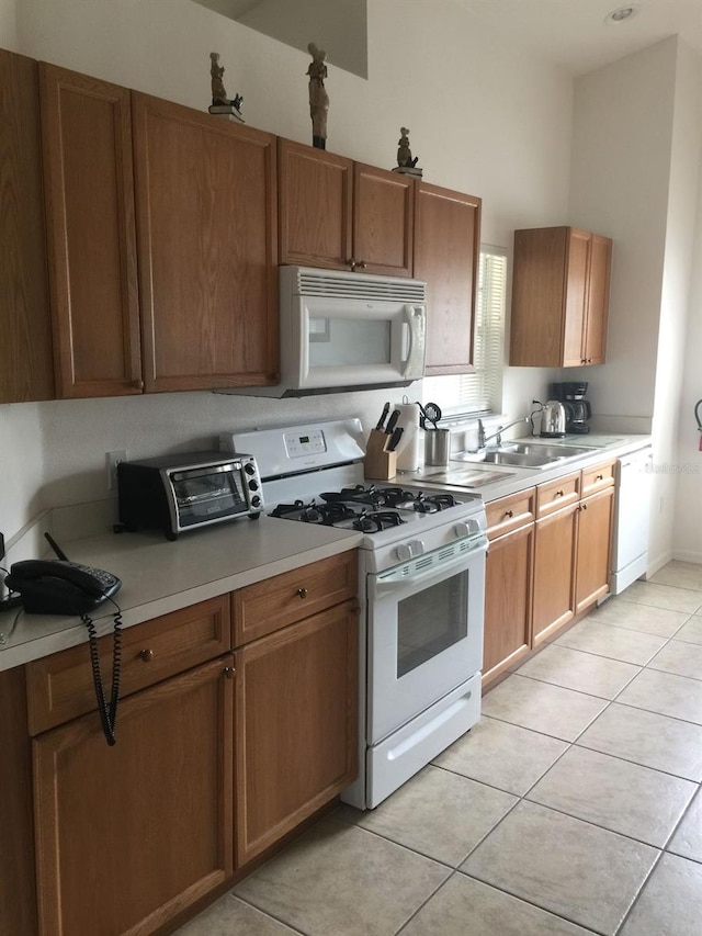 kitchen with white appliances, light tile patterned floors, and sink