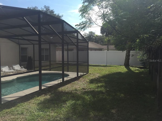 view of pool featuring a patio area, a yard, and a lanai