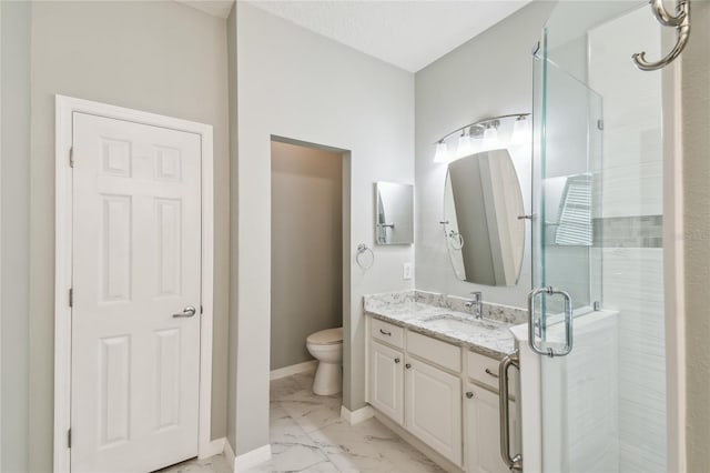 bathroom with toilet, vanity, and a shower with shower door