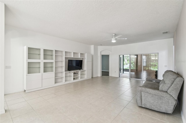 540 Genoa Dr, Poinciana, FL 34759 - living room featuring a ceiling fan, light tile patterned floors, a textured ceiling, arched walkways, and baseboards