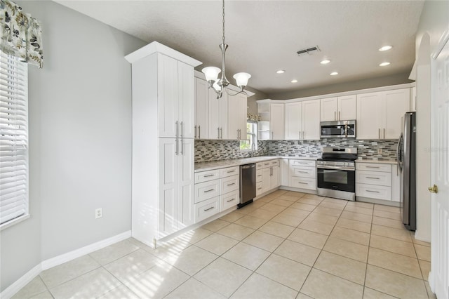 kitchen with stainless steel appliances, light tile patterned flooring, white cabinetry, decorative light fixtures, and backsplash