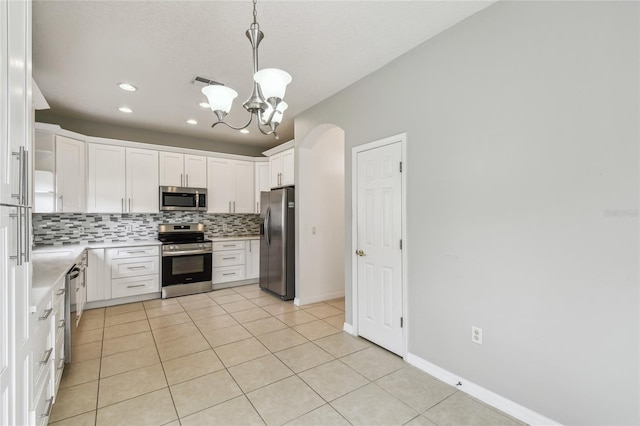 kitchen with stainless steel appliances, white cabinets, light tile patterned floors, tasteful backsplash, and pendant lighting