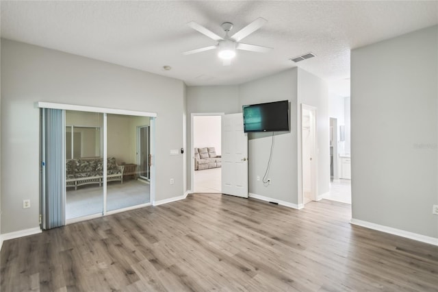 unfurnished bedroom with a closet, a textured ceiling, hardwood / wood-style flooring, and ceiling fan