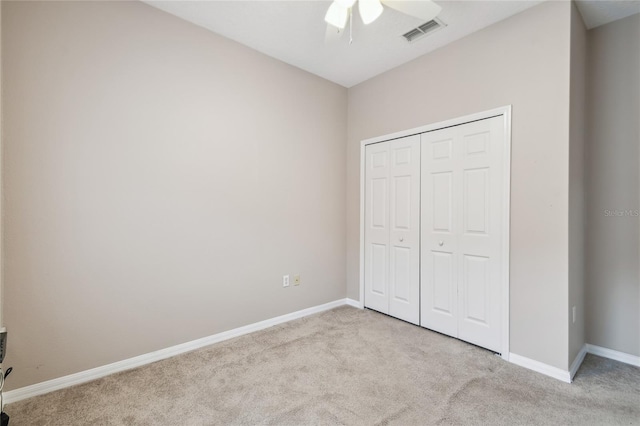 unfurnished bedroom with ceiling fan, light carpet, and a closet