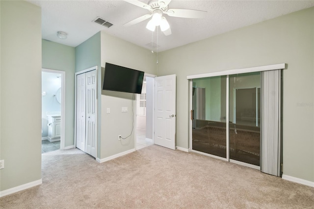 unfurnished bedroom with a textured ceiling, light colored carpet, ceiling fan, and connected bathroom