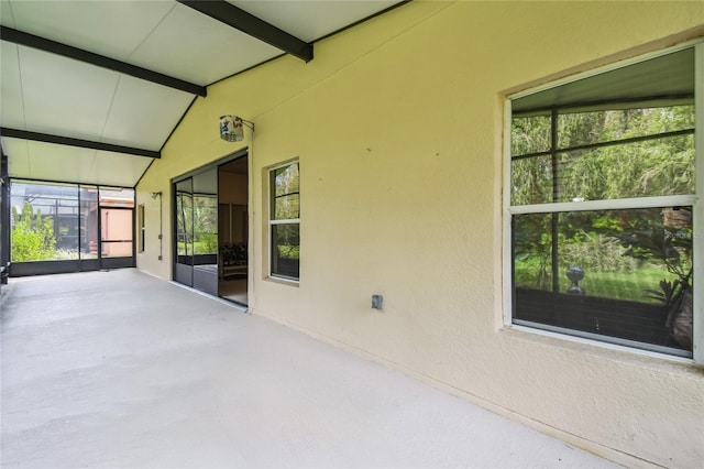 unfurnished sunroom featuring lofted ceiling with beams