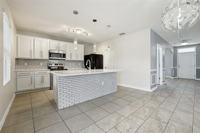 kitchen featuring stainless steel appliances, white cabinetry, and a kitchen island with sink