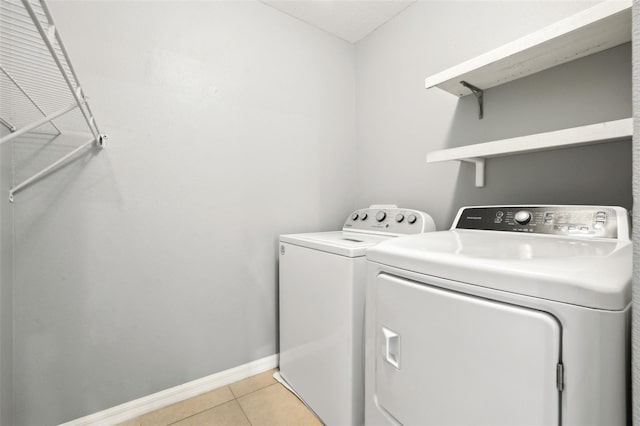 clothes washing area with washing machine and clothes dryer and light tile patterned floors