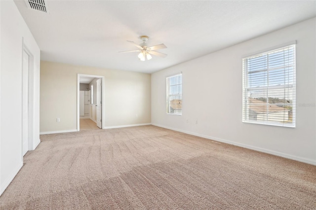 empty room with ceiling fan, light colored carpet, and a wealth of natural light