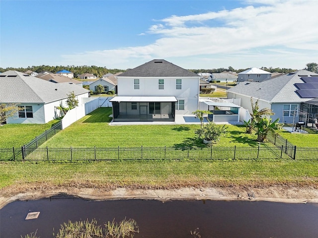 rear view of house featuring a lawn, a water view, a sunroom, and a patio area