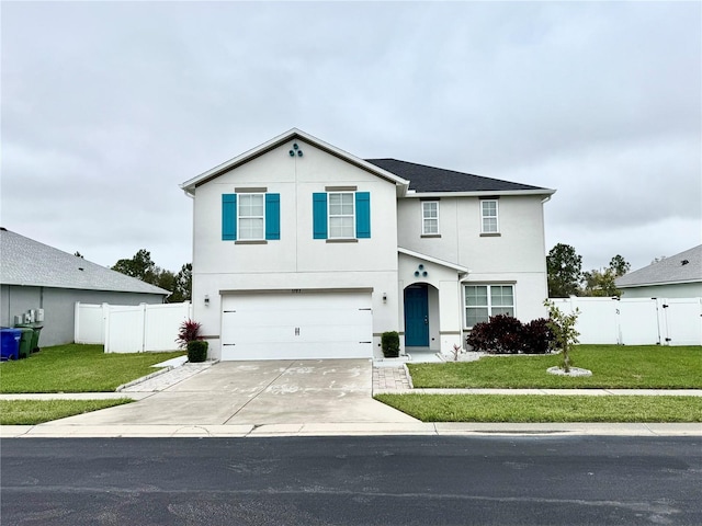 traditional-style home featuring an attached garage, fence, concrete driveway, stucco siding, and a front yard