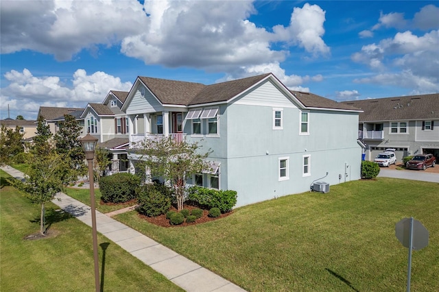 view of front of property featuring central AC unit, a front yard, a garage, and a balcony