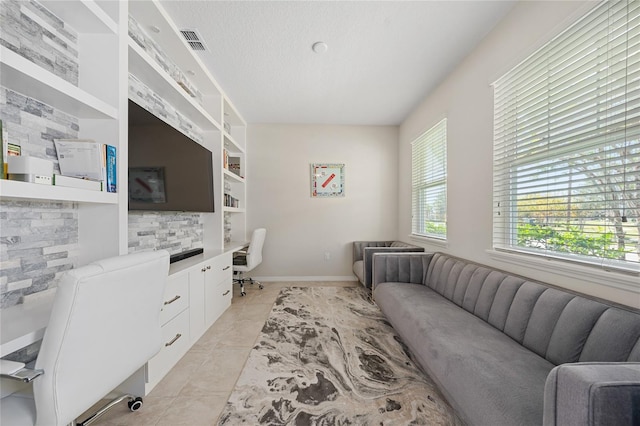 living room with a textured ceiling, built in features, built in desk, and light tile patterned floors