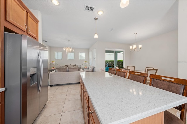 kitchen with light tile patterned flooring, a kitchen island, stainless steel fridge with ice dispenser, pendant lighting, and an inviting chandelier