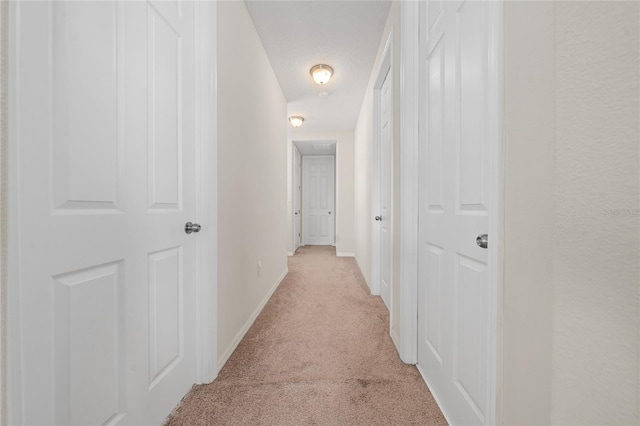 hall featuring a textured ceiling and light carpet