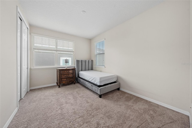 bedroom with a textured ceiling, light carpet, and a closet