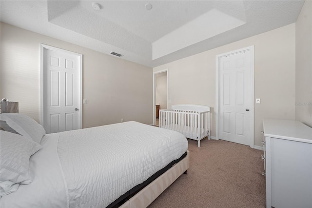 bedroom with a tray ceiling, a textured ceiling, and carpet flooring