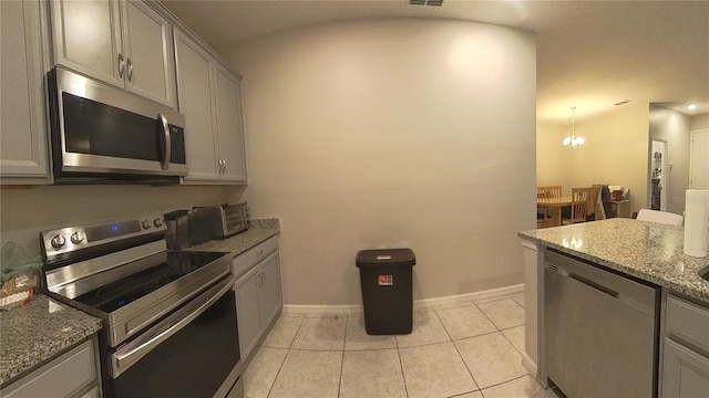 kitchen with light stone counters, a chandelier, gray cabinets, light tile patterned floors, and appliances with stainless steel finishes