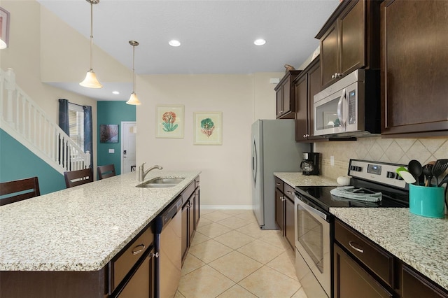 kitchen with light stone counters, sink, tasteful backsplash, an island with sink, and appliances with stainless steel finishes